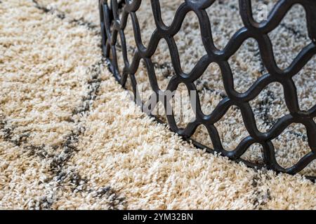 A black and white rug with a white base and a black metal base is placed on a white carpet. The rug has a unique design that adds a touch of elegance Stock Photo