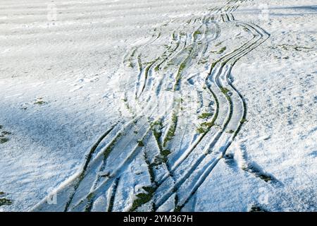 Snow buggy tracks in snow with footprints Stock Photo