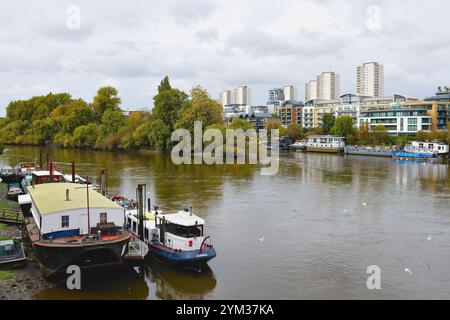 The River Thames as viewed from Kew bridge looking towards Brentford riverside with moored houseboats and modern apartments Greater London England UK Stock Photo