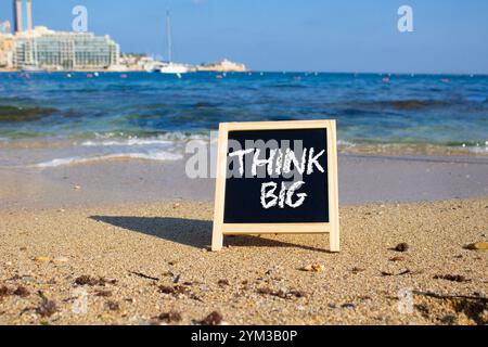 Think big symbol. Concept words Think Big on black chalk background. Beautiful sea background. Business and Think big concept. Copy space. Stock Photo