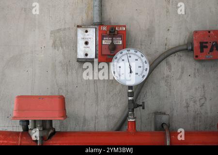 Pressure gauges or pressure manometer mounted on the pipeline and signal FIRE ALARM system, wire tubes attached on wall. Stock Photo