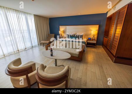 Elegant hotel room in Mexico featuring modern wooden furniture, cozy seating, large bed and natural lighting. Cancun. Mexico. Stock Photo