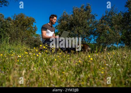 Young Backpacker Working Remotely in Nature with Laptop Stock Photo