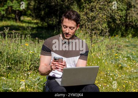 Digital Nomad: Young Man Backpacker Using Laptop and Phone Stock Photo