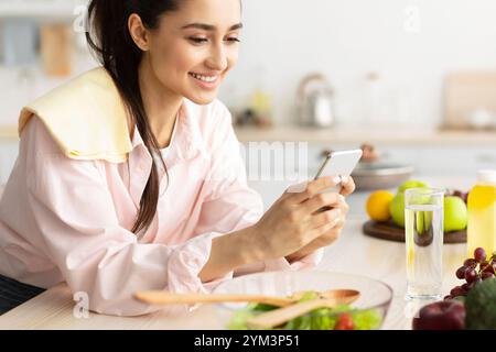 Portrait of smiling young woman using cellphone in kitchen Stock Photo
