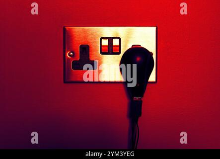 UK wall electric plug (brushed silver) with 5V power adapter with red background Stock Photo
