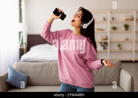 Young woman singing using smartphone as mic Stock Photo