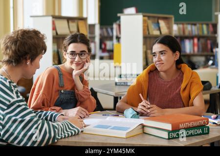 Discussing Class Project in School Library in Afternoon Stock Photo
