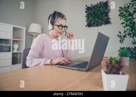 Photo of adorable sweet lady wear pink sweatshirt headphones talking modern device indoors room home house Stock Photo