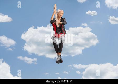 Woman with a guitar sitting on a cloud up in the sky Stock Photo