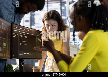 IT staff members doing brainstorming, conducting tests in computer to optimize machine learning models for performance and accuracy. Team of developers talking in office, analyzing complex AI data Stock Photo