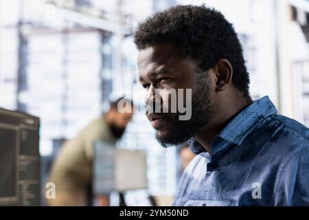 Admin squinting eyes, trying to better see while reading source code on computer, doing software quality assurance. IT expert focused on inspecting coding on PC, looking to fix potential issues Stock Photo