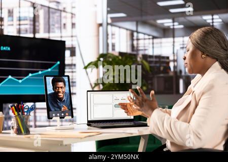 Businesswoman in videoconference meeting with cheerful man, analyzing market trends and data metrics. Entrepreneur talking with specialist in videocall, developing trading strategies and algorithms Stock Photo