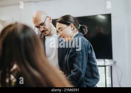 Students collaborating on project with professor in modern classroom setting Stock Photo