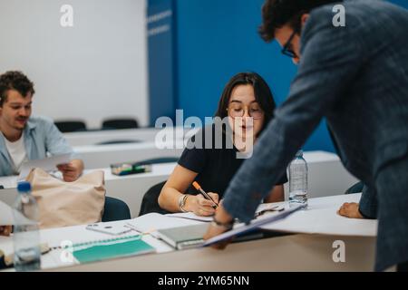 Professor assists students during classroom task in academic setting Stock Photo