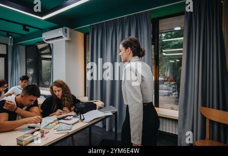 Teacher engaging with attentive students in a modern classroom setting Stock Photo