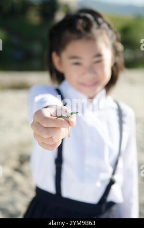 Primary school girl holding out a twin leaf Stock Photo