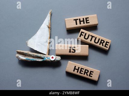 The future is here symbol. Concept words The future is here on wooden blocks. Beautiful grey background with boat. Business and The future is here con Stock Photo