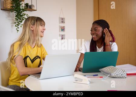 Multiethnic students collaborating on project using laptops at home Stock Photo