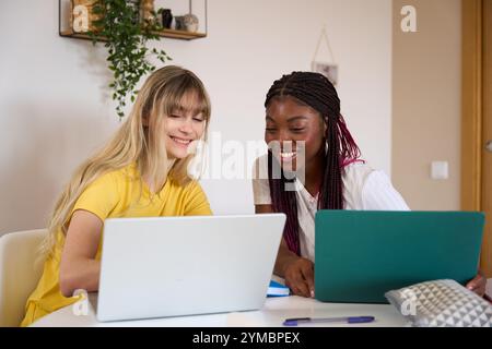 Multiethnic students collaborating on project using laptops at home Stock Photo