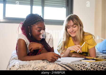 Multiethnic students collaborating on studies in bedroom: sharing knowledge and achieving academic success Stock Photo