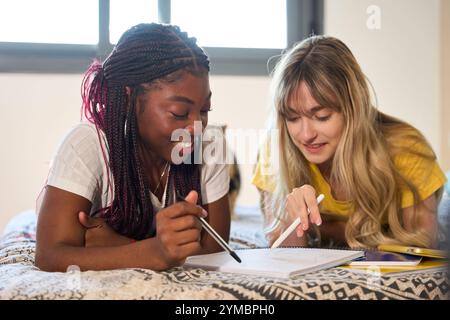 Multiethnic students collaborating on project, studying together in bedroom Stock Photo