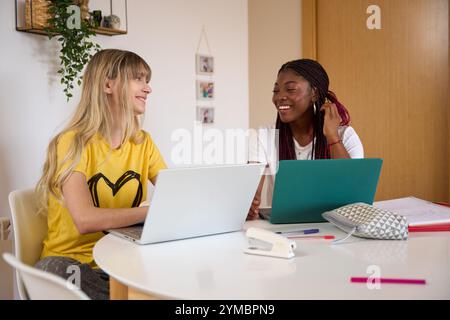 Multiethnic students collaborating on project using laptops at home Stock Photo