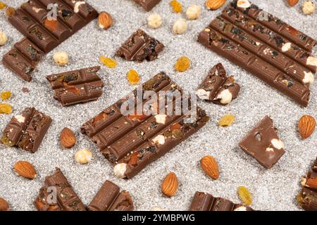 Broken chocolate pieces with nuts and raisins on a stone background top view Stock Photo