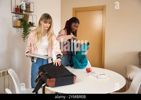 Multiethnic students preparing backpacks for university in apartment Stock Photo