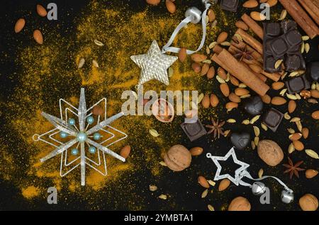Christmas decorations, spices, seeds, nuts and sweets on a black table; top view, kitchen. Stock Photo