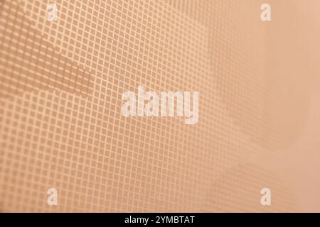 Subtle, textured grid pattern, creating a minimalist and modern abstract background. The soft, peachy hue adds a touch of warmth and elegance Stock Photo