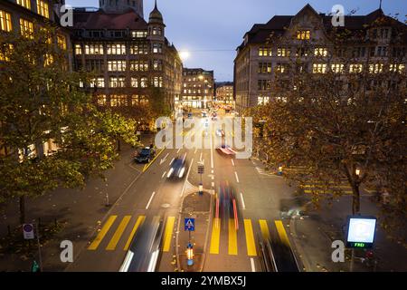 Car traffic on busy street with pedestrian crossing at night in a city in Europe. Above view, blurred moving cars and people. Stock Photo