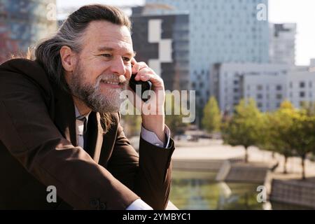 smiling middle age man with beard talking on phone Stock Photo