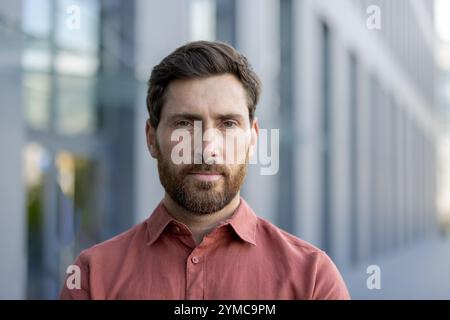 Mature businessman outdoors in an urban area, wearing smart casual attire. Captures confident, thoughtful expression with urban, modern atmosphere. Stock Photo
