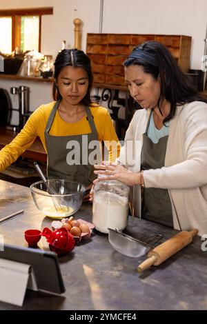 Grandmother and asian female teenager baking together in kitchen, preparing treats, at home Stock Photo