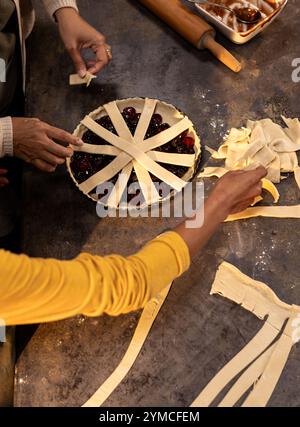 Grandma and asian female teenager preparing cherry pie together at home Stock Photo