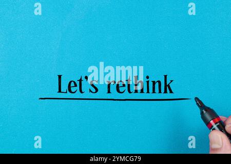 Concept words LET'S RETHINK written on blue background. Beautiful red table, red background. Businessman hand. Business concept. Copy space. Stock Photo