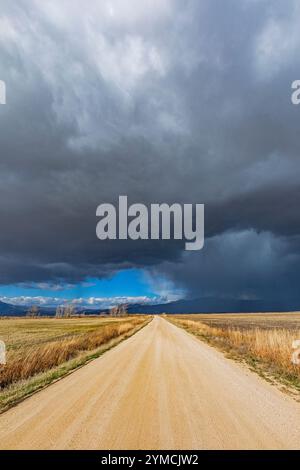 Storm clouds over empty dirt road in rural landscape Stock Photo