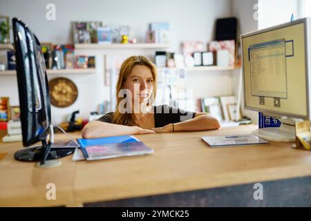 Portrait of woman leaning on desk in office Stock Photo