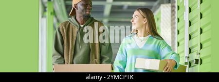 Website header shot of cheerful African American man chatting with girlfriend moving cardboard boxes into self storage unit during apartment declutter Stock Photo