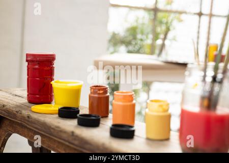 Colorful paint jars on rustic table, ready for creative art project, at home Stock Photo