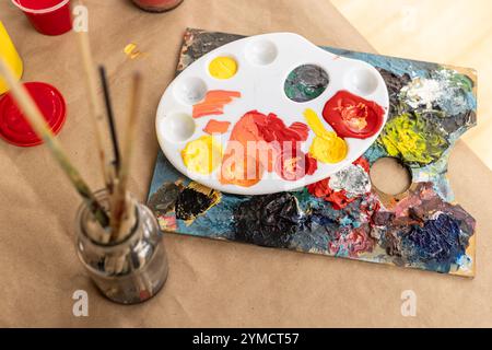 Colorful paint palette and brushes on table, ready for creative art project, at home Stock Photo