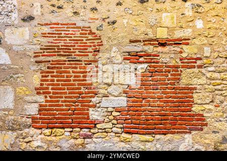 An old repair or rebuilding of a stone wall with red bricks - Angles-sur-l'Anglin, Vienne (86), France. Stock Photo