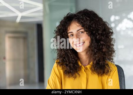 Happy woman in modern office setting. Bright smile conveys confidence, positivity in workplace. Ideal for business, professional, inspiration concepts. Stock Photo