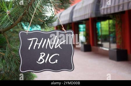 Think big symbol. Concept words Think Big on black chalk blackboard. Beautiful background with shop and tree. Business and Think big concept. Copy spa Stock Photo