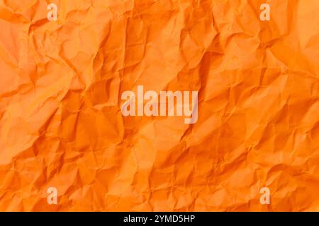 Top view and full frame of wrinkled or crumpled orange paper is used as crumpled orange paper background texture. Stock Photo