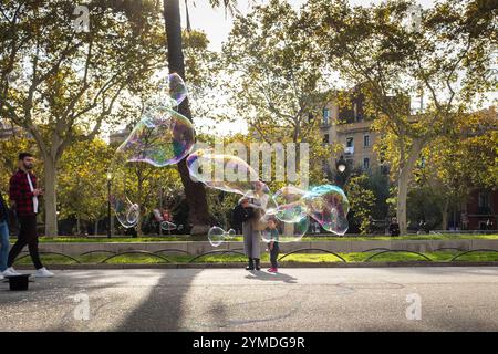 Tourists, children and locals alike walk by and engage with the street art of a 'Bubble' man along the Passeig de Lluís Companys in Barcelona city, SP. Stock Photo