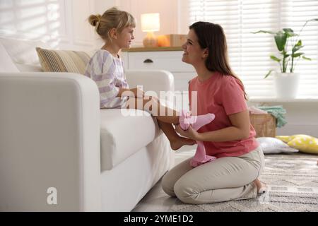 Mother helping her daughter to put tights on at home Stock Photo