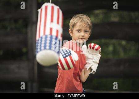 Cute boy boxing bag in the garden during sunny afternoon Stock Photo