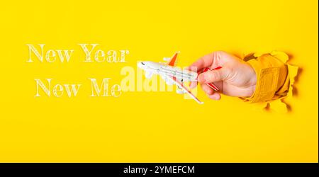 Hand holding a toy airplane with the words New Year Now Me written below it. Concept of excitement and new beginnings as the year starts Stock Photo